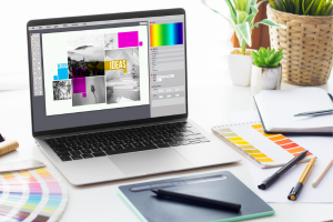 Laptop displaying a graphic design project with creative tools on the desk.